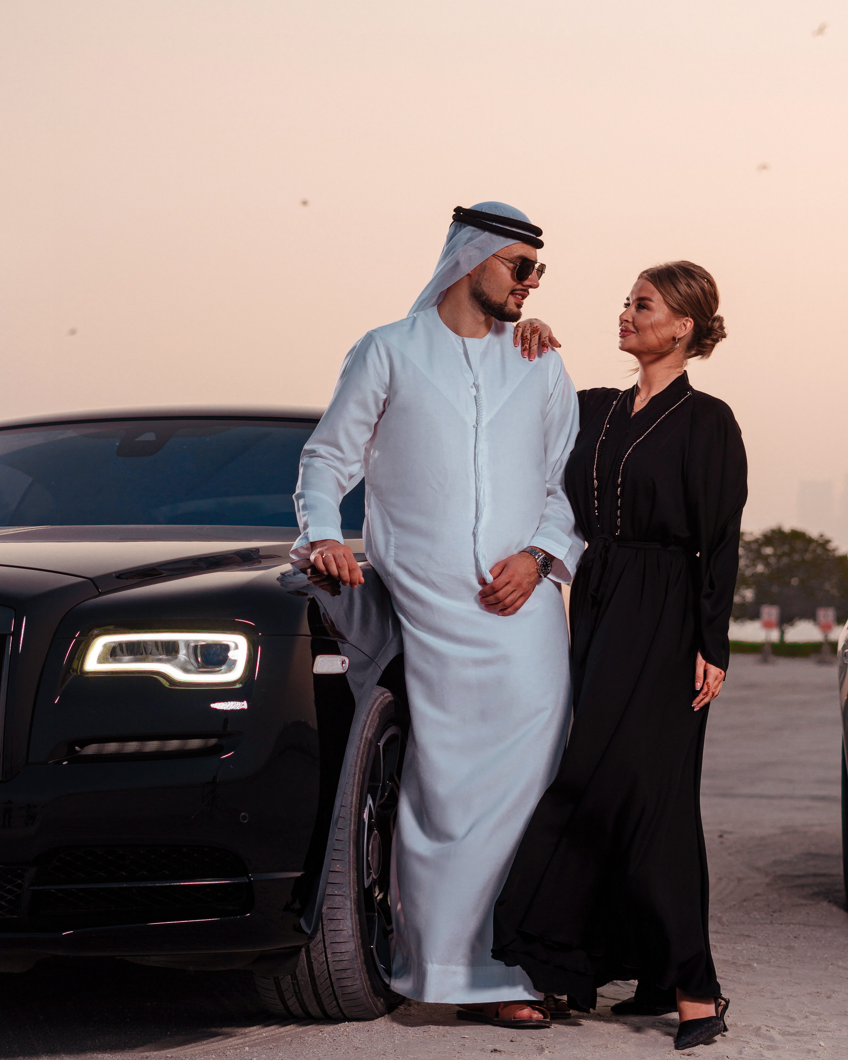 A man and woman posing during a luxury car photoshoot next to a Rolls Royce in Dubai.